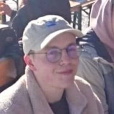 Foto von Philipp Parzer grinsend mit Adlerlagune Cap auf der Alm